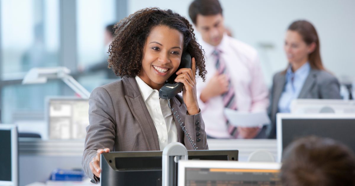 Young businesswoman in a silver suit jacket making a call using a VoIP package