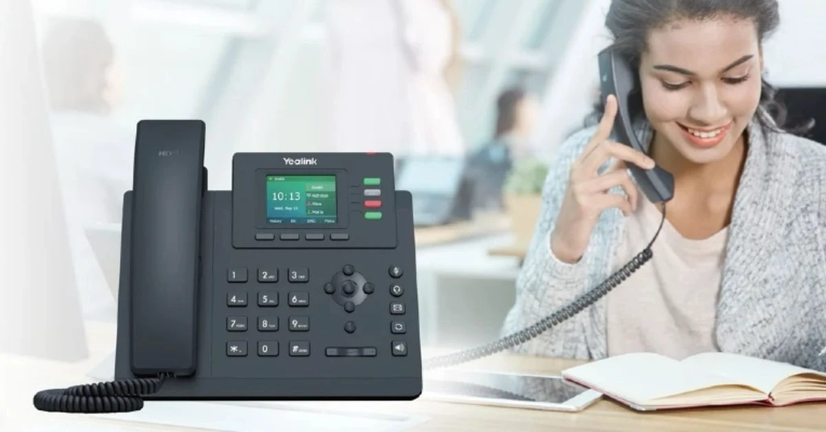 Business professional using a Yealink desk phone in an office.