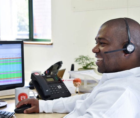 United Telecoms employee smiling and talking to a customer with a headset on