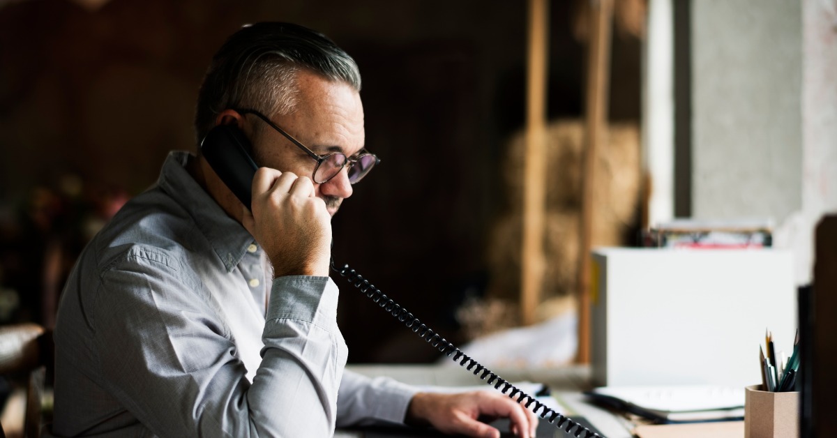 A businessman making a call using his deskphone and on-premise PBX system.