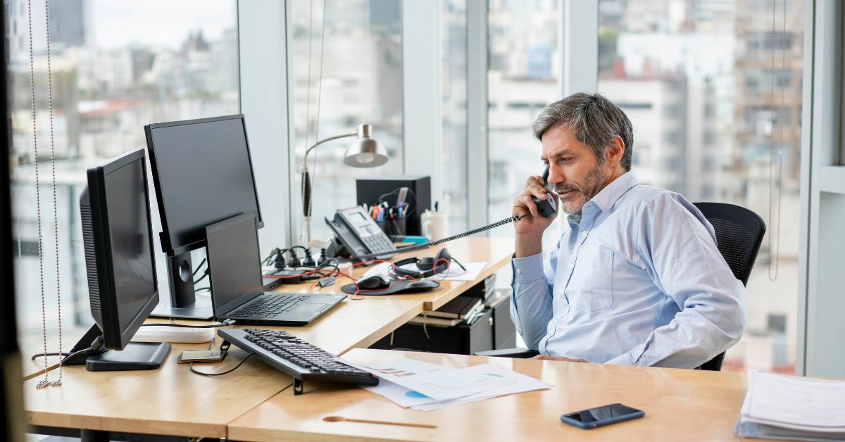 Manager seated at desk taking a call on a VoIP phone