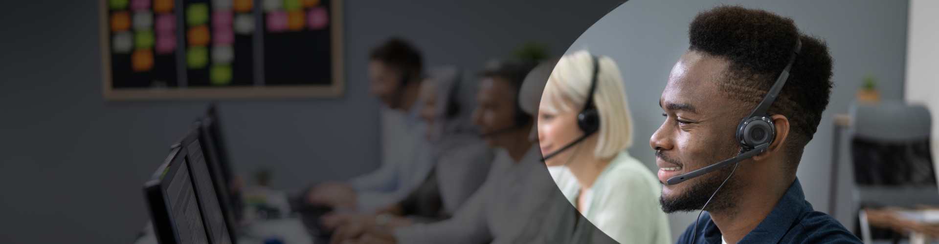 A call centre agent seated at his desk using a Snom phone headset