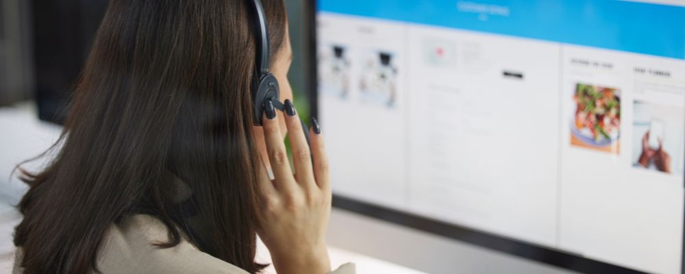 A woman on a call with a customer whilst simultaneously managing PBX features in real time.