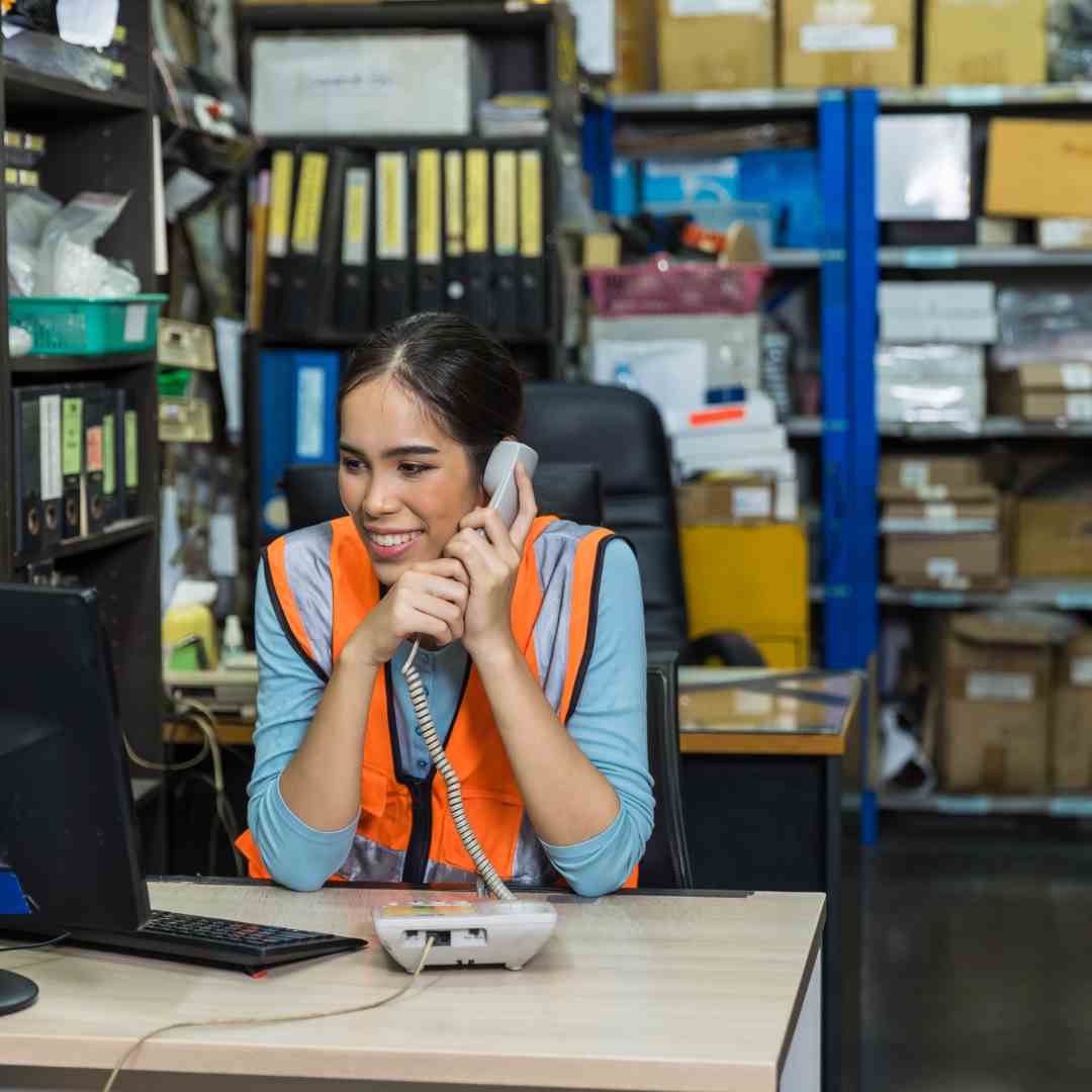 Woman warehouse staff worker speaking with colleague using a Fanvil phone