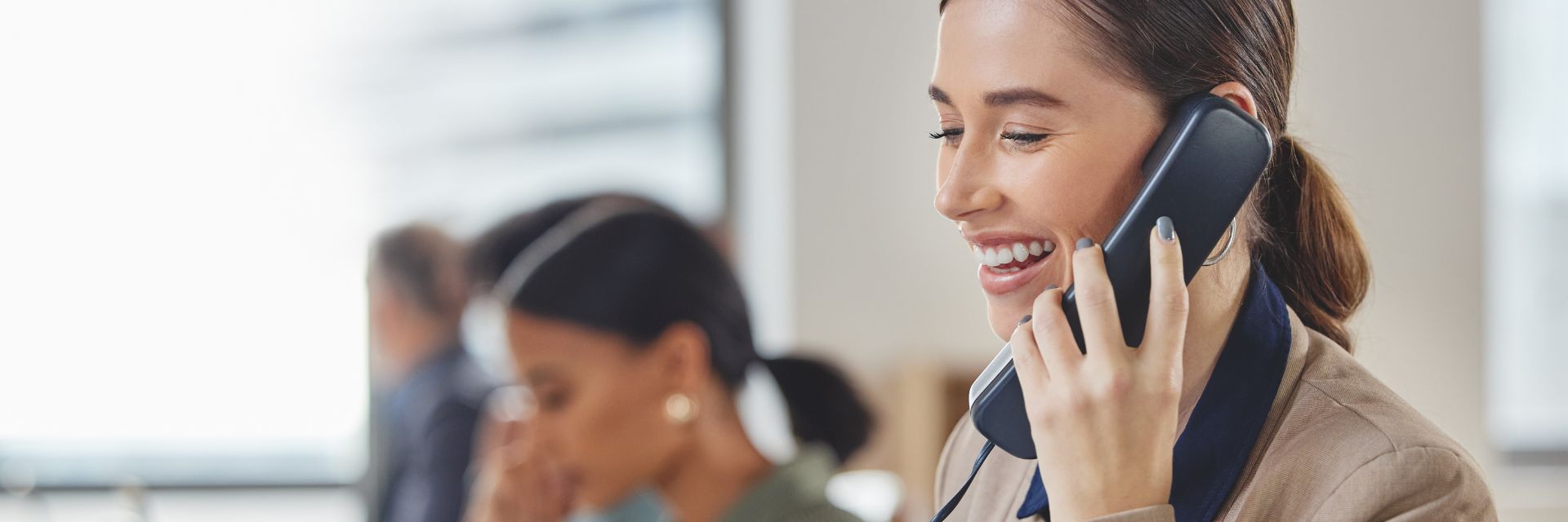 Business professional taking a call on a Yealink phone in an office.
