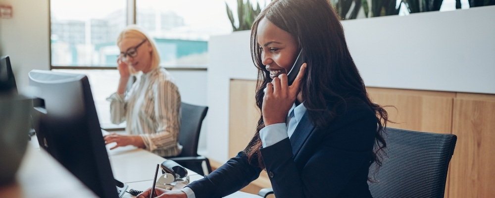Black business woman wearing a black suit and making a call with a SIP-enabled phone