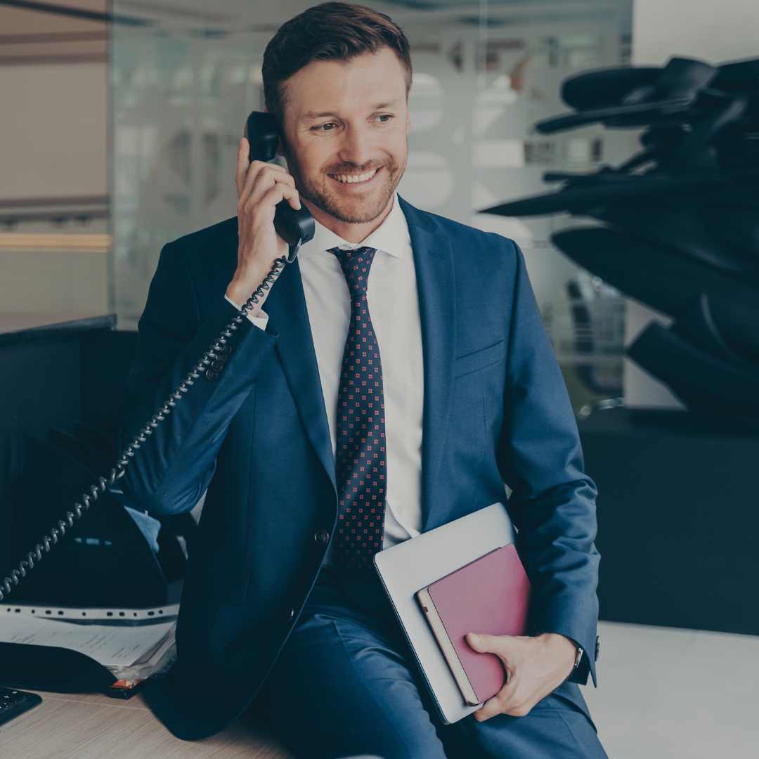 A business executive, seated on his desk, using a Snom phone