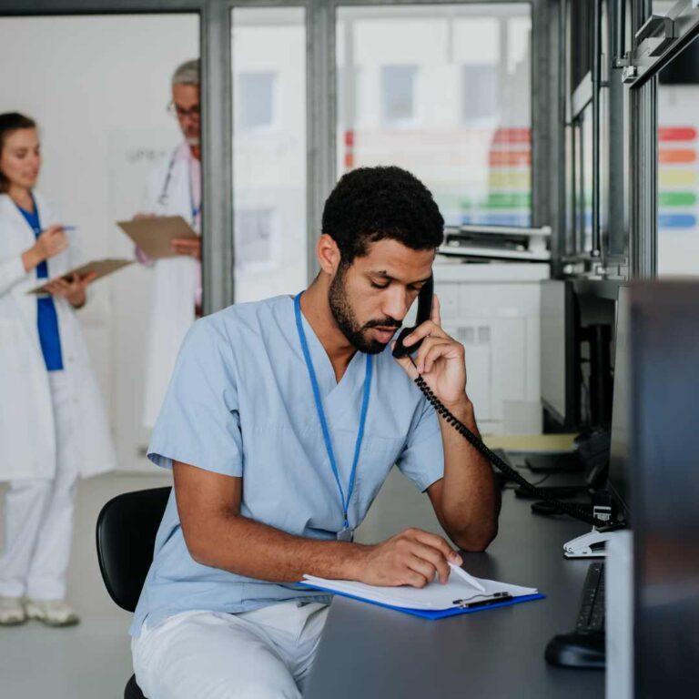 A healthcare worker, at his desk, using a Snom phone