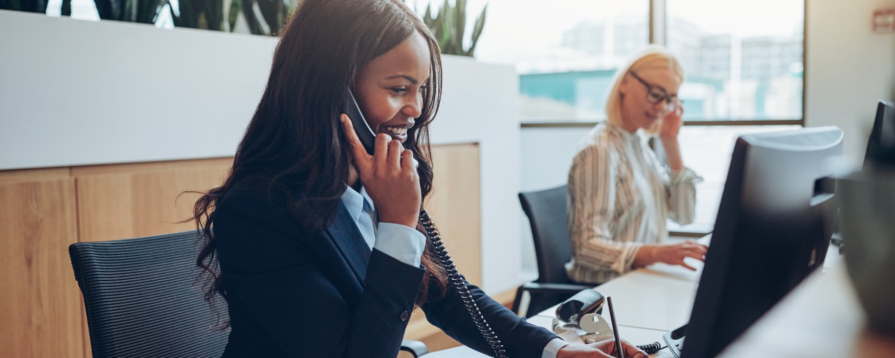Business woman taking a call and working on computer using business fibre connection
