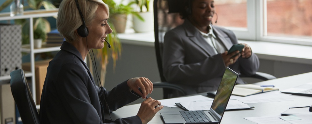 Woman in black jacket speaking with a client using headsets and a VoIP package