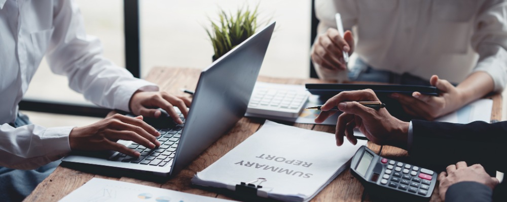 Business managers seated at a table calculating business fibre costs for their Durban office branch